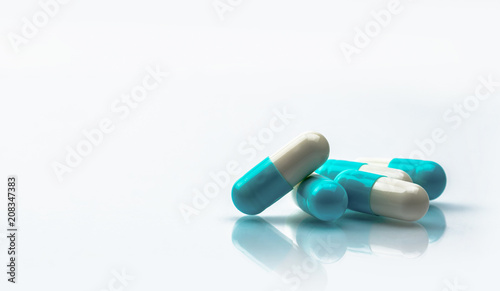 Blue and white capsules pill isolated on white background with shadow and copy space. Global healthcare concept. Antibiotics drug resistance. Antimicrobial capsule pills. Pharmaceutical industry.