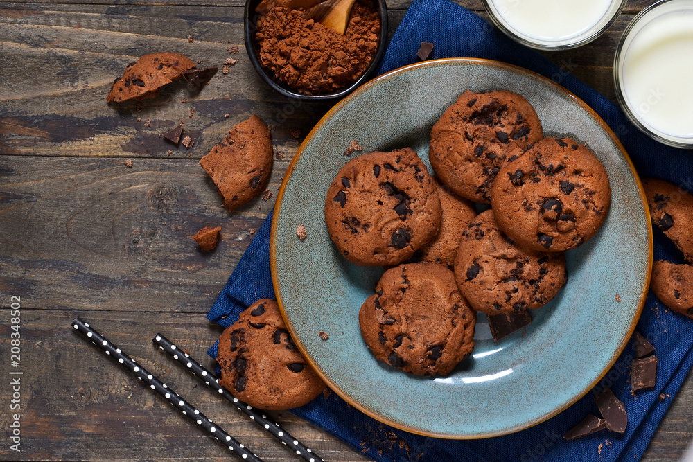 Fototapeta premium Homemade chocolate cookies in a plate with milk on a wood background.