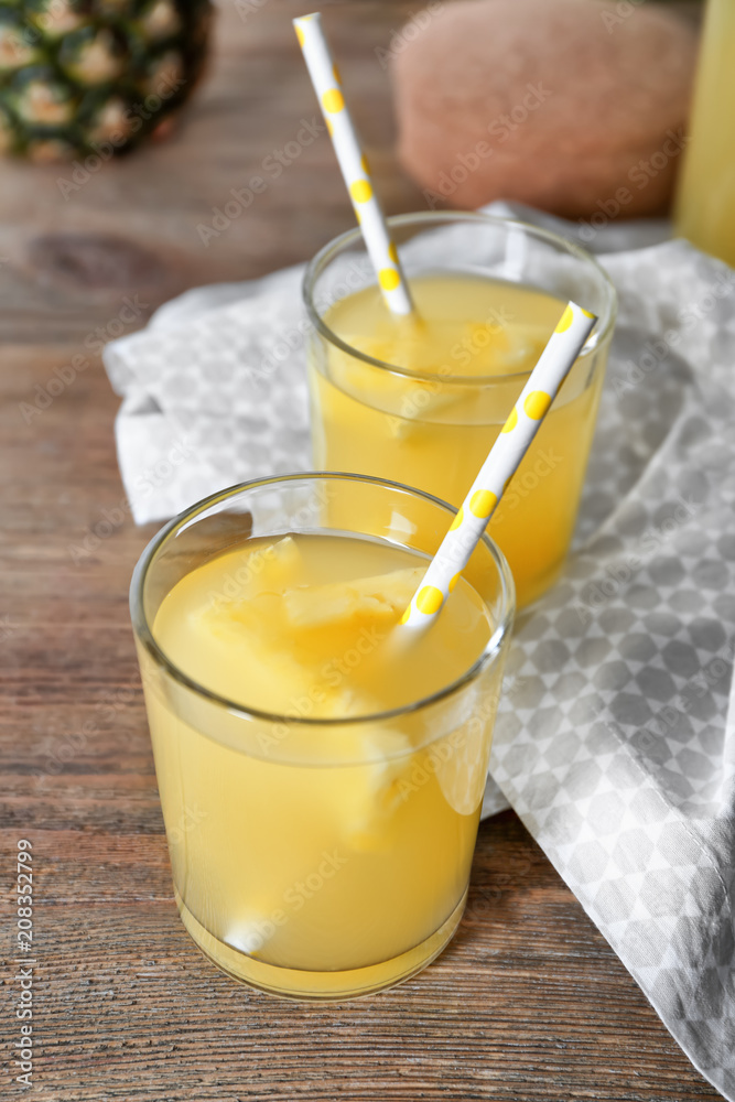 Fototapeta premium Glasses of tasty fresh pineapple juice on wooden table
