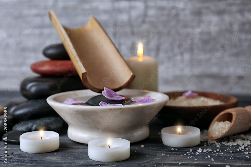 Spa composition with water in bowl and candles on table Spa composition with water in bowl and candles on table