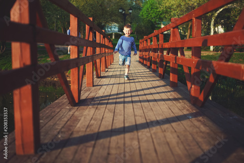 funny boy running on wooden bridge