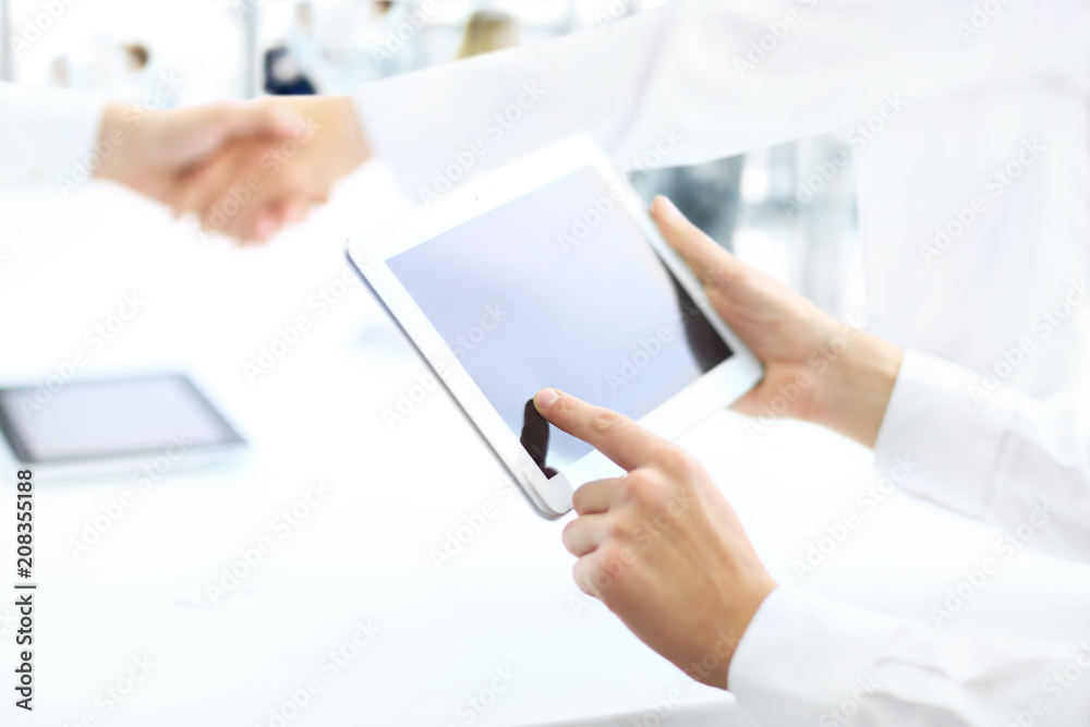 Business partners handshake in the office. Hands on with the tablet in the foreground Business partners handshake in the office. Hands on with the tablet in the foreground