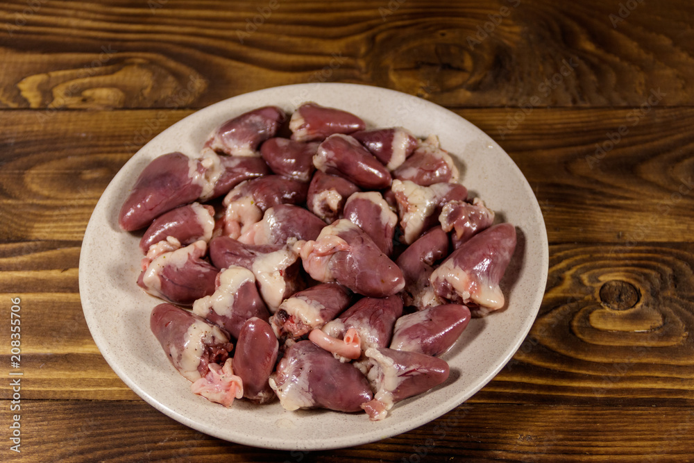 Raw chicken hearts on wooden table