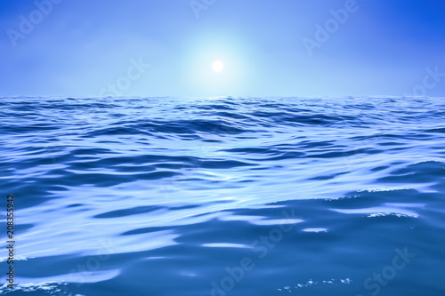 a blue ocean with sun over the horizon