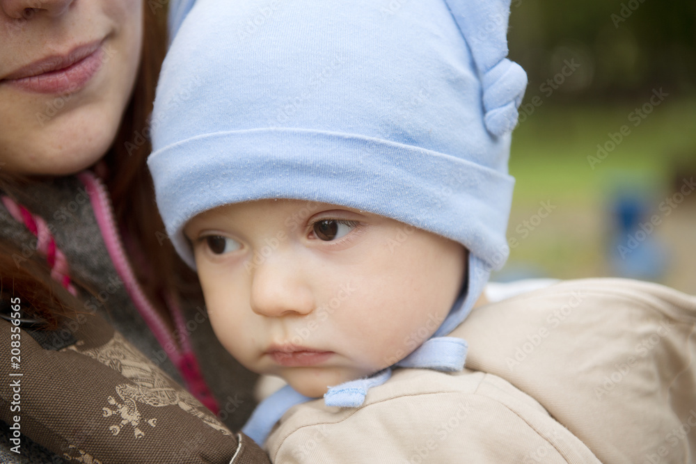Portrait of a child boy in the arms of a mother with a serious face close-up. Portrait of a child boy in the arms of a mother with a serious face close-up.