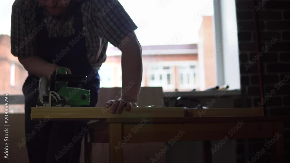 The process of building a wooden table, the carpenter saw off the bars for the legs or base. The process of building a wooden table, the carpenter saw off the bars for the legs or base.