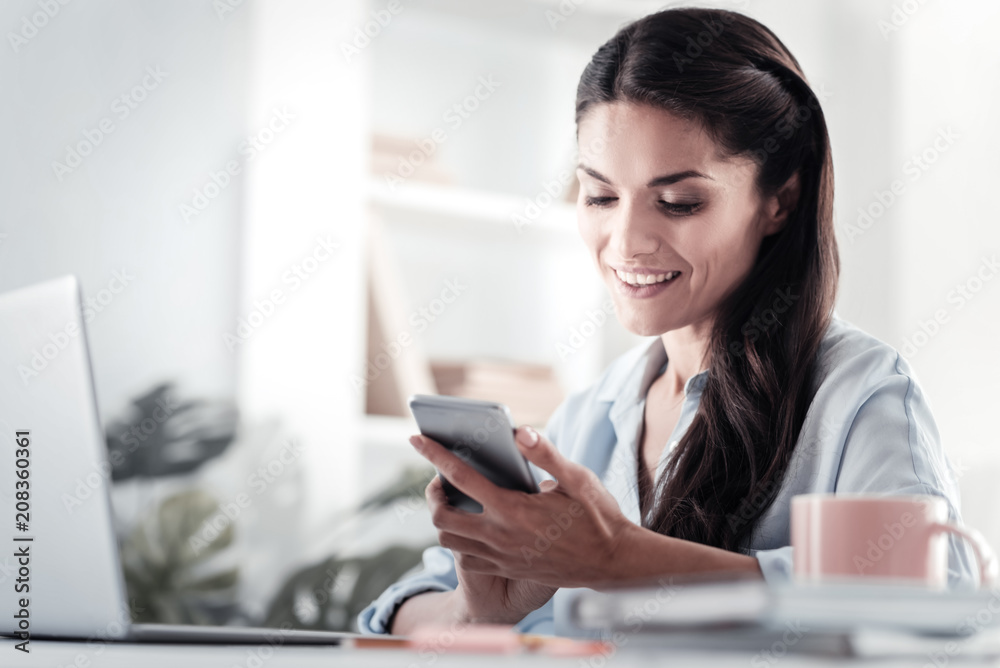 Pleasant thoughts. Attractive woman smiling while reading message Pleasant thoughts. Attractive woman smiling while reading message