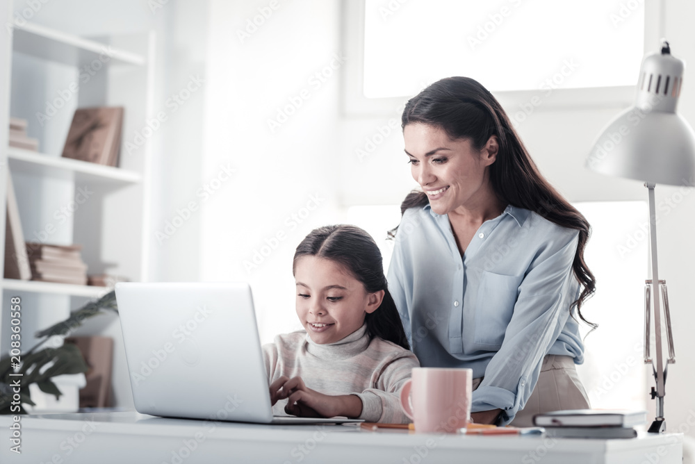 Let me help. Charming young woman keeping smile on her face while staring at computer Let me help. Charming young woman keeping smile on her face while staring at computer