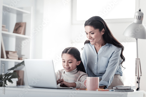 Let me help. Charming young woman keeping smile on her face while staring at computer