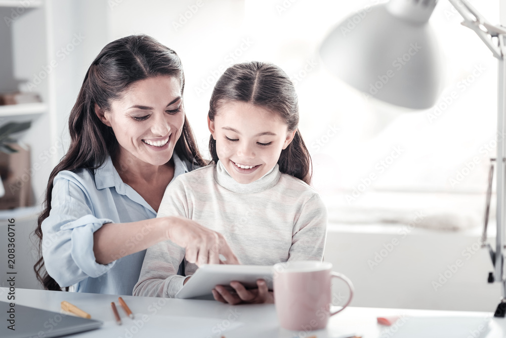 Just imagine. Charming girl keeping smile on her face while looking at her gadget Just imagine. Charming girl keeping smile on her face while looking at her gadget