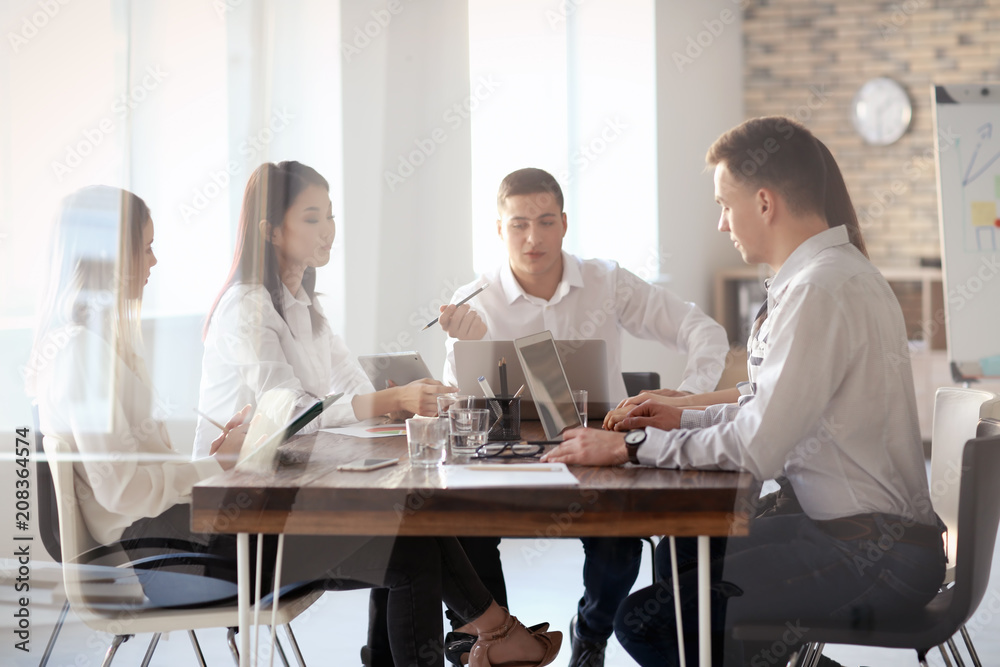 Young people having business meeting in office, view through glass Young people having business meeting in office, view through glass