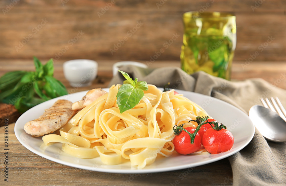 Plate of delicious pasta with grilled chicken fillet and tomatoes on table Plate of delicious pasta with grilled chicken fillet and tomatoes on table
