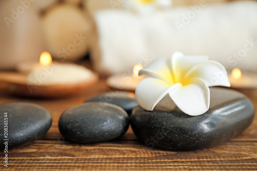 Spa stones and beautiful flower on wooden table  closeup