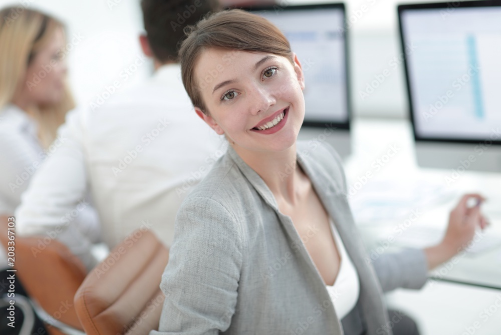 rear view. beautiful business woman sitting near the desktop and looking at the camera. rear view. beautiful business woman sitting near the desktop and looking at the camera.