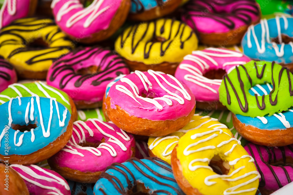 Many colorful donuts, background of different color cakes