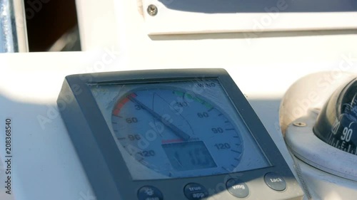 Sailing boats instrument by the steering wheel showing wind direction and speed. Closeup on windex and some rotating blurred steering wheel. photo