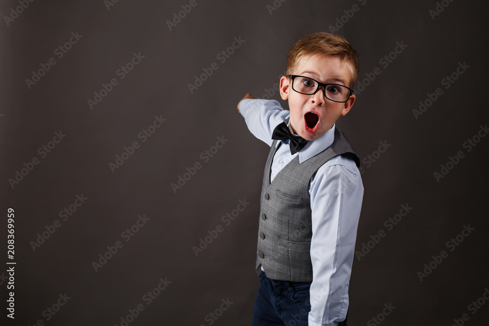 Shocked little boy in a suit shows something on the background Shocked little boy in a suit shows something on the background