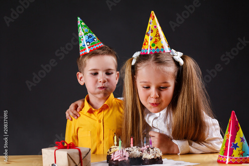 Little boy and girl take off candles from the birthday cake before eating it photo