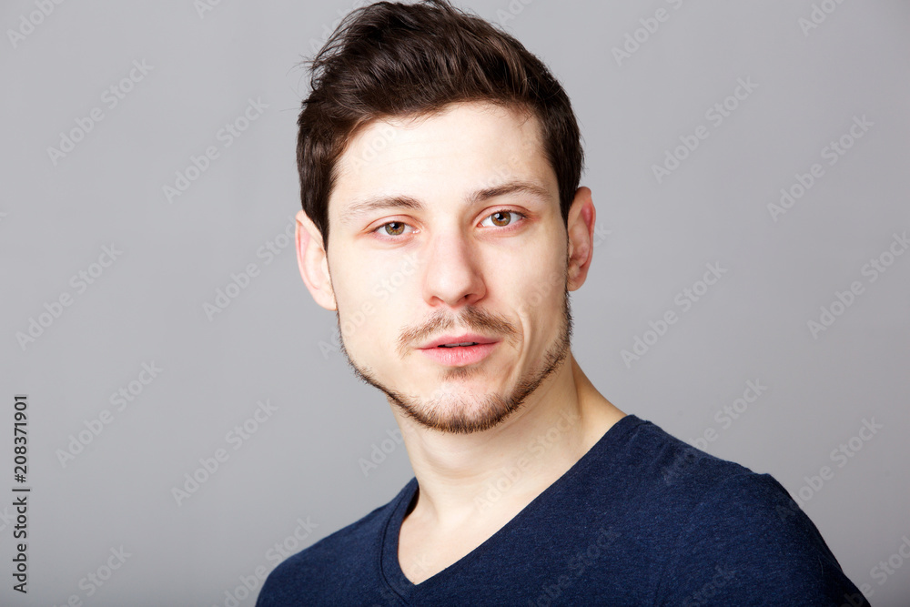Fototapeta premium young man with serious expression against gray background