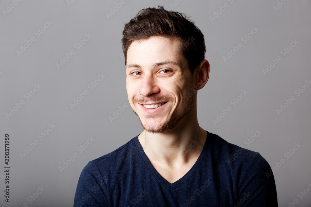 handsome young man smiling against gray background handsome young man smiling against gray background