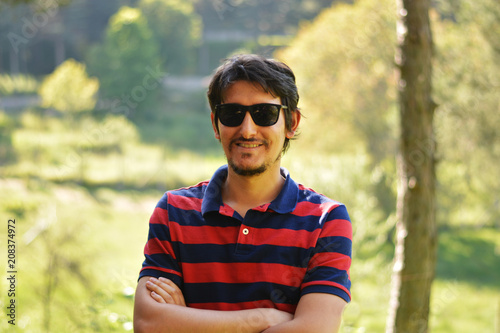Young man's outdoors portrait looking at the camera with natural green background. Neutral, happy, sad, disgust, fear, surprise Facial Emotions.