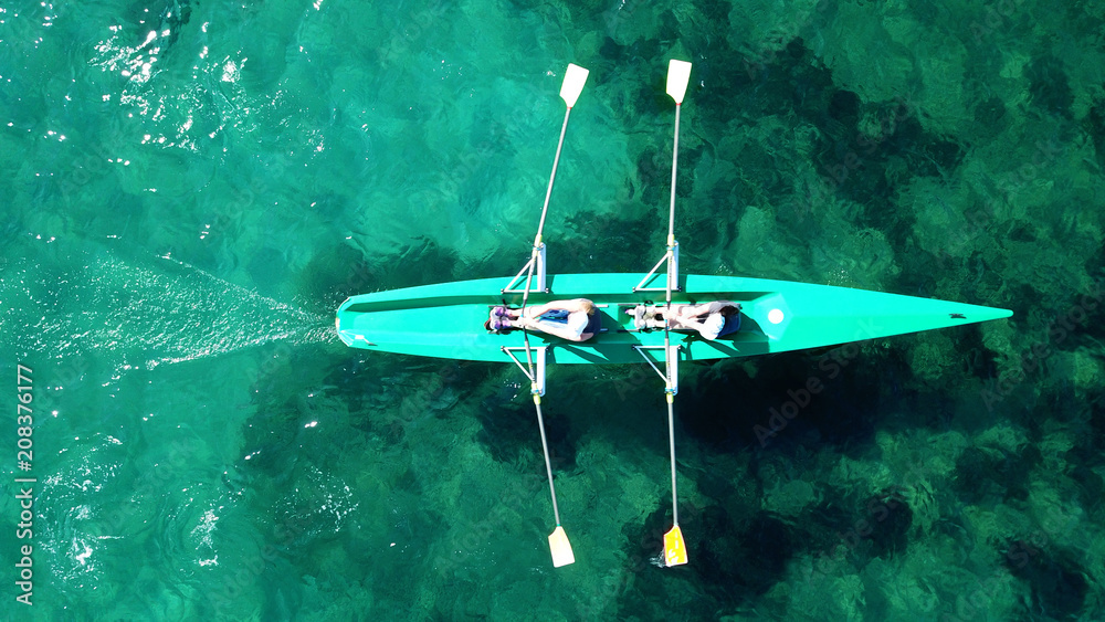 Fototapeta premium Aerial drone bird's eye view of sport canoe operated by 2 young women in turquoise clear waters