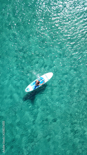 Aerial drone bird's eye view of a man exercising sup board in turquoise tropical clear waters at sunset © aerial-drone