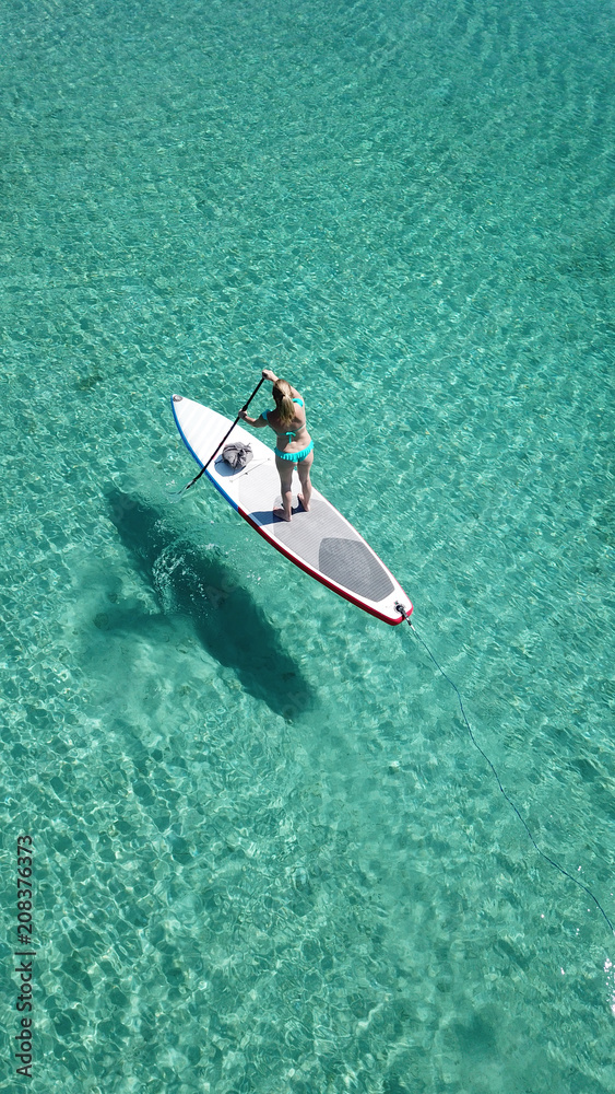 Fototapeta premium Aerial photo of woman on sup or paddle surf in tropical caribbean turquoise clear water beach