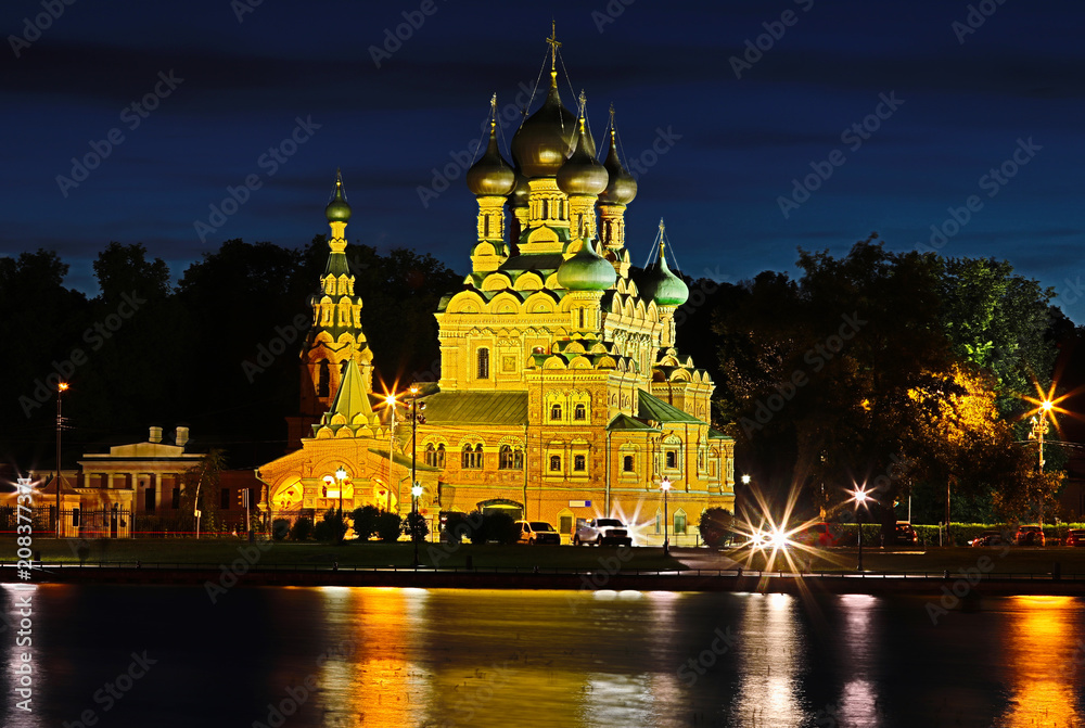The view on the church or temple near the pound or lake with the trees in Ostankino in the light of setting sun. 