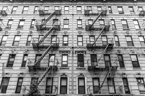 A fire escape of an apartment building in New York city. Graphical black and white image.