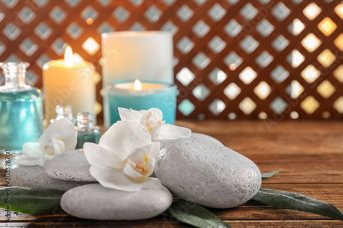 Spa stones with beautiful flowers on wooden table