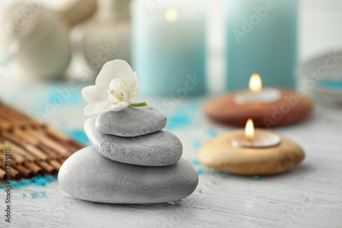 Stack of spa stones with beautiful flower on table