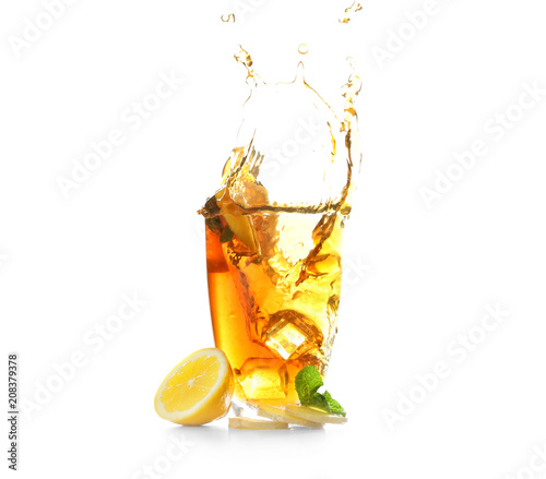 Glass and splash of delicious lemon tea with ginger on white background