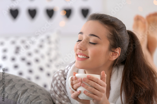 Fototapeta Naklejka Na Ścianę i Meble -  Beautiful young woman with cup of hot tea at home