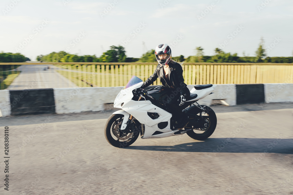 Woman biker driving a motorbike on a road