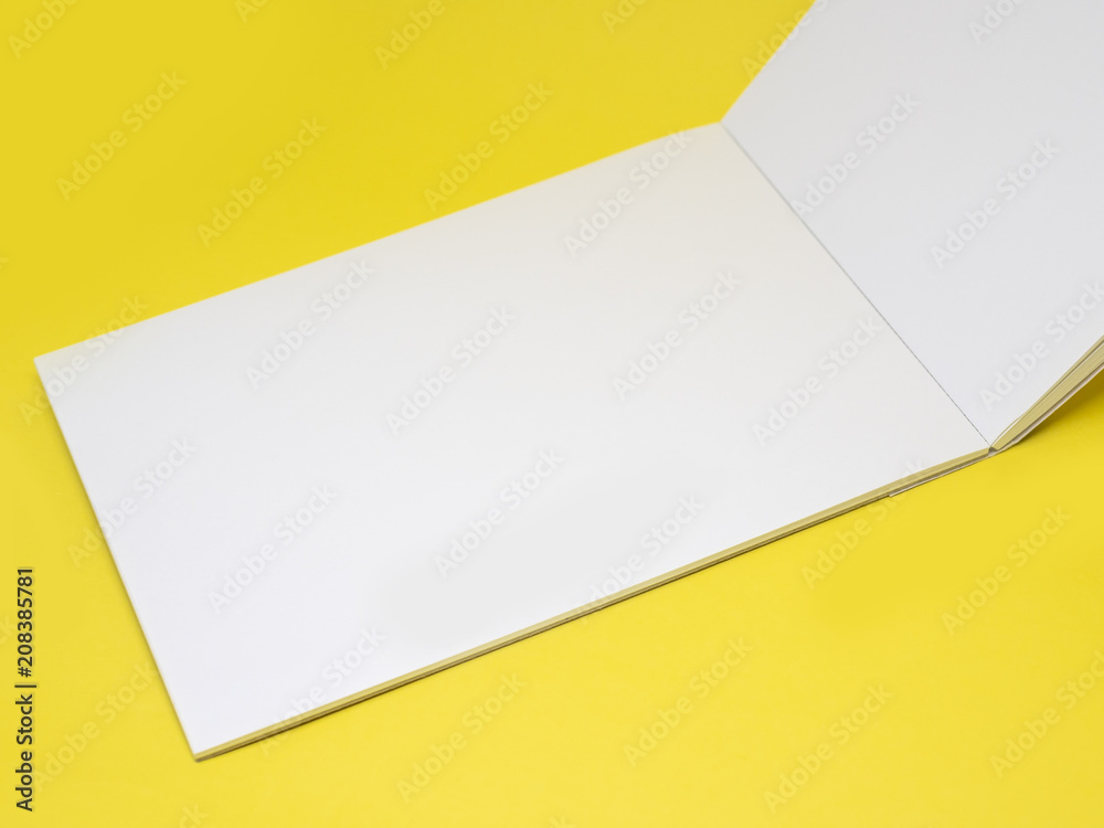 Vertically open blank notepad on a yellow background, close up Vertically open blank notepad on a yellow background, close up