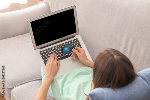Young woman with credit card using laptop at home