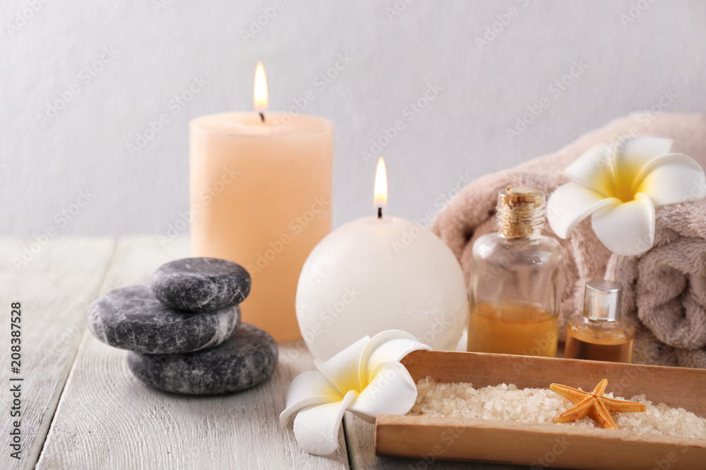 Spa composition with sea salt, candles and rolled towels on light background Spa composition with sea salt, candles and rolled towels on light background