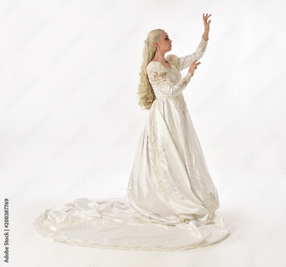 full length portrait of blonde woman wearing long white bridal gown. standing pose on white studio background. full length portrait of blonde woman wearing long white bridal gown. standing pose on white studio background.