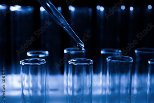 Pipette dripping sample into test tube on dark background, closeup © Pixel-Shot