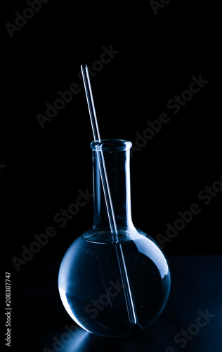 Volumetric flask with liquid and pipette on black background © Pixel-Shot