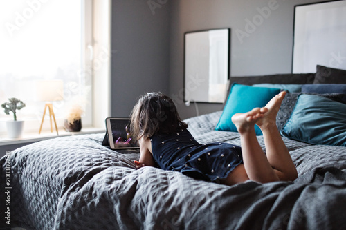 Girl lying on bed watching tablet photo
