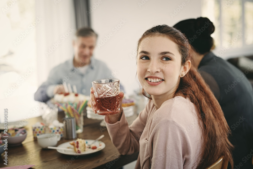 Smiling girl having drink while sitting with family at table during party Smiling girl having drink while sitting with family at table during party
