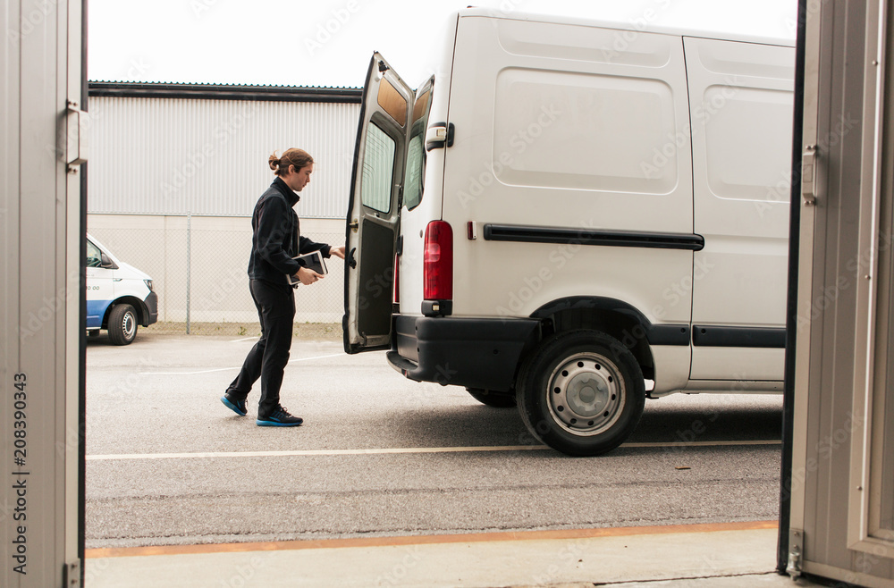 Side view of manual worker closing delivery van while standing on road Side view of manual worker closing delivery van while standing on road
