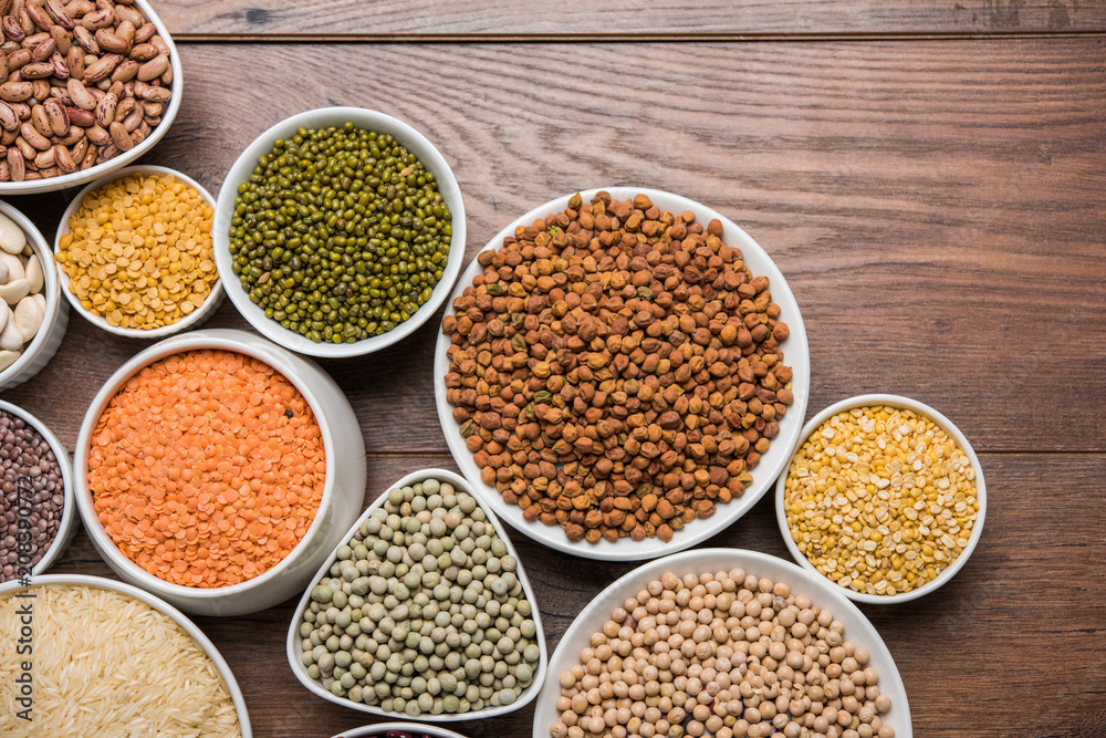 Uncooked pulses,grains and seeds in White bowls over wooden background. selective focus Uncooked pulses,grains and seeds in White bowls over wooden background. selective focus