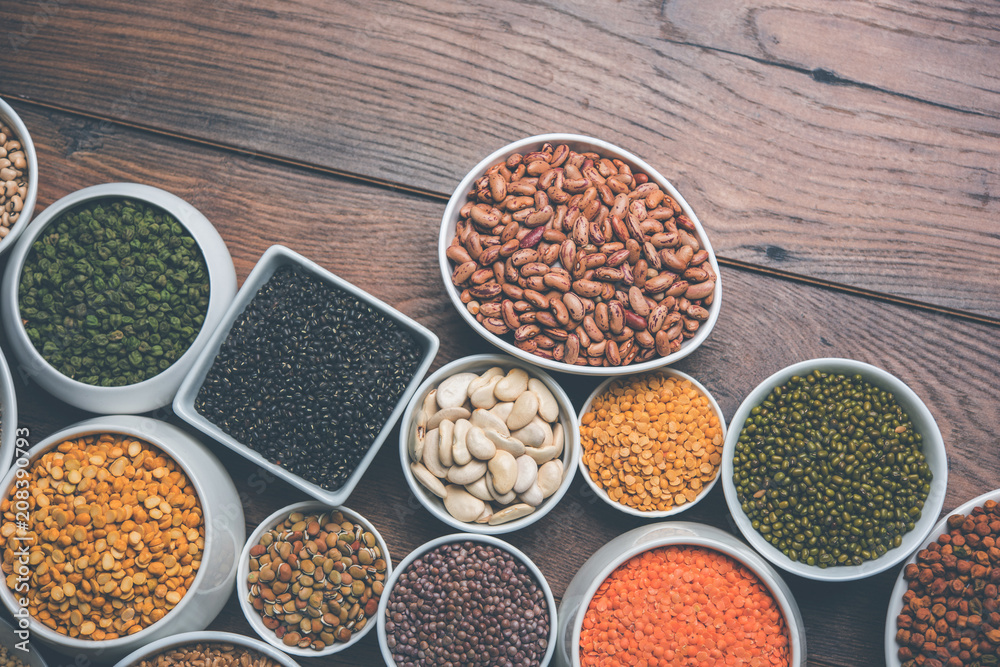 Uncooked pulses,grains and seeds in White bowls over wooden background. selective focus