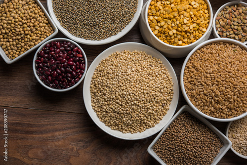 Uncooked pulses,grains and seeds in White bowls over wooden background. selective focus