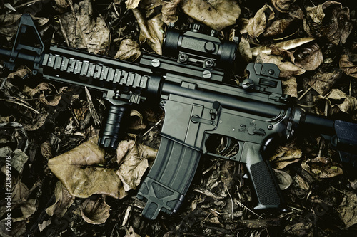 Obraz na płótnie Weapons and military equipment for army, Assault rifle gun (M4A1) on dry leaves forest background. w salonie
