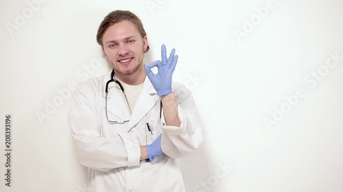 Male vet in white gown and blue medicalgloves showing OK Having stethoscope on neck. photo