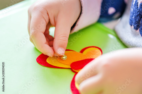 Child making felt soft toy of green leaf and red ladybag . Child DIY activity. Close-up. Children handicraft concept photo